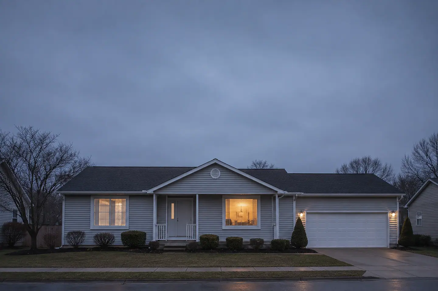 A repaired American home at dusk with lights on after restoration work.