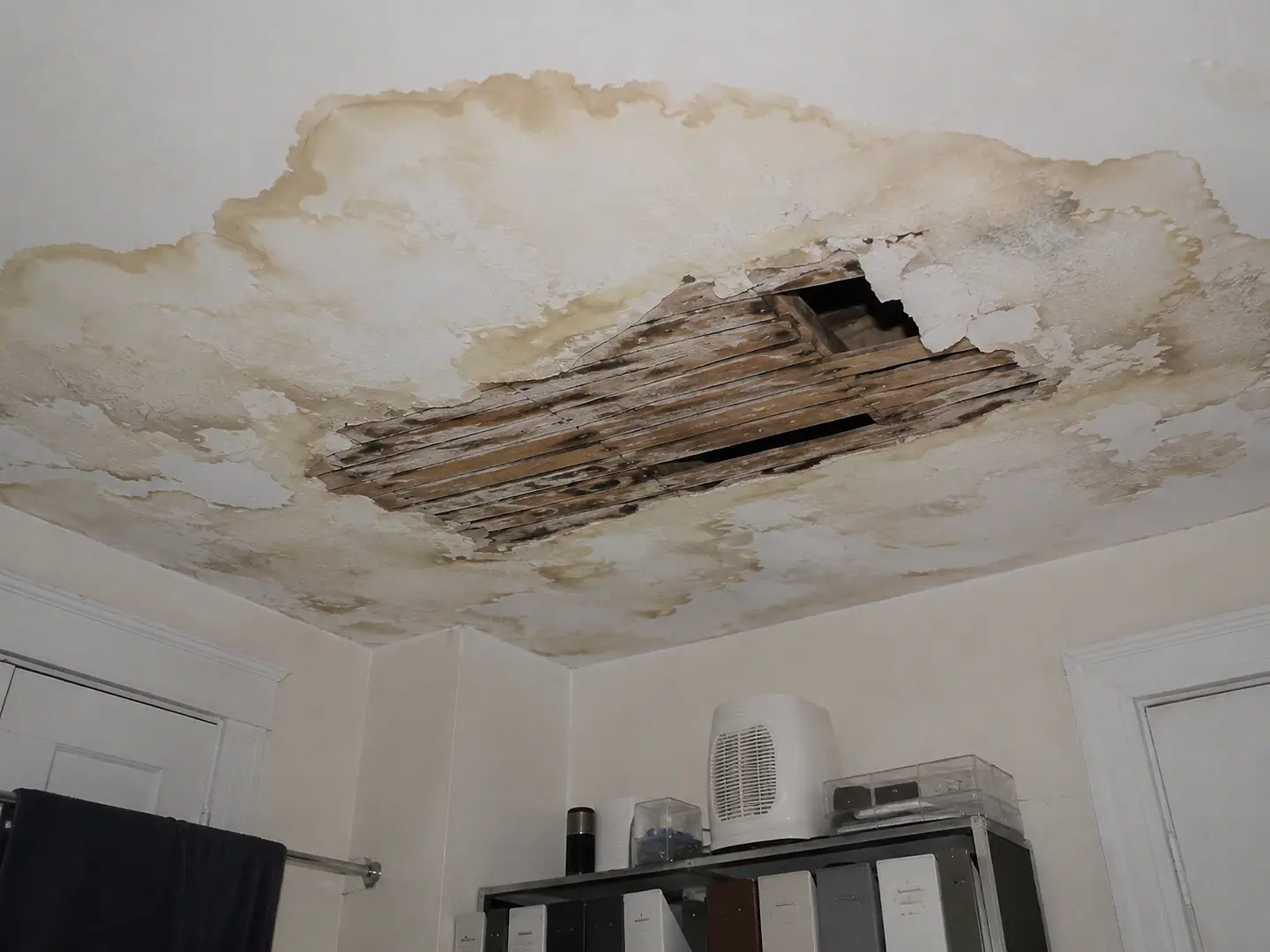 A residential ceiling that has collapsed and stained following prolonged water damage.